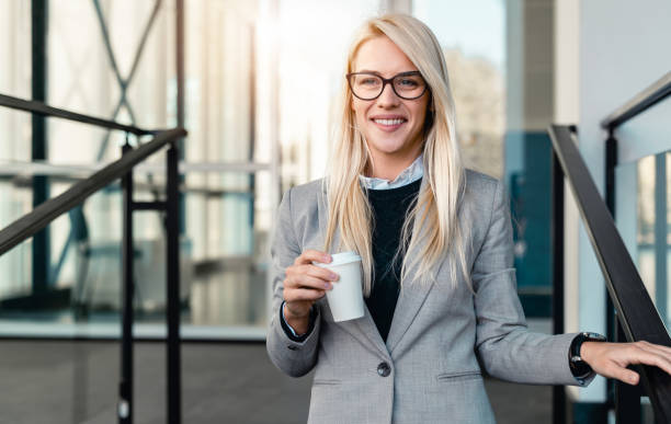 istock Beautiful smiling businesswoman looking at camera while walking down a staircase in an office building 1949816742