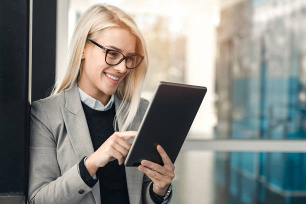 istock CEO female white collar worker with glasses using digital tablet while standing outside the office 1949817342