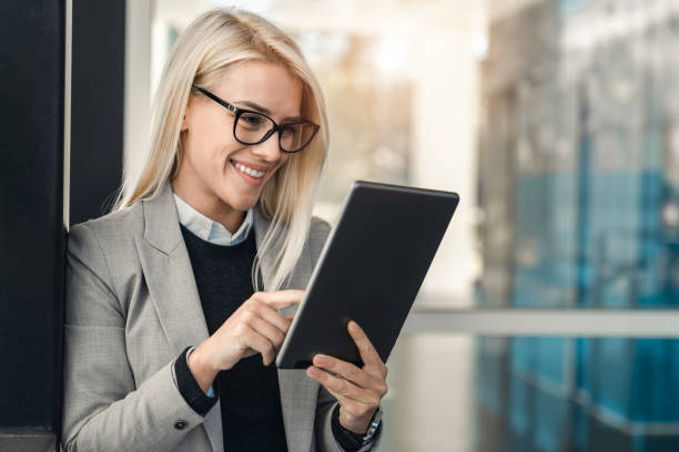 istock Blond businesswoman with eyeglasses using digital tablet while standing in an office 1949823601