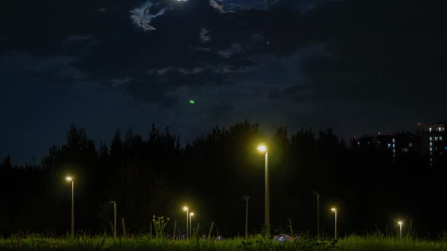 Time lapse. Evening city park, the moon rises into the night sky.