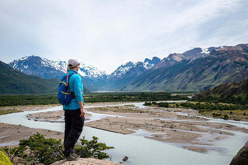 Tourist looking towards a snowy mountain in the distance. Young man in southern Argentina. Young tourist on vacation in El Chalten, Argentina. Tourist in Patagonia Argentina