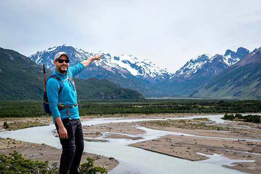 Tourist pointing finger at snowy mountain in the distance. Young man in southern Argentina. Young tourist on vacation in El Chalten, Argentina. Tourist in Patagonia Argentina