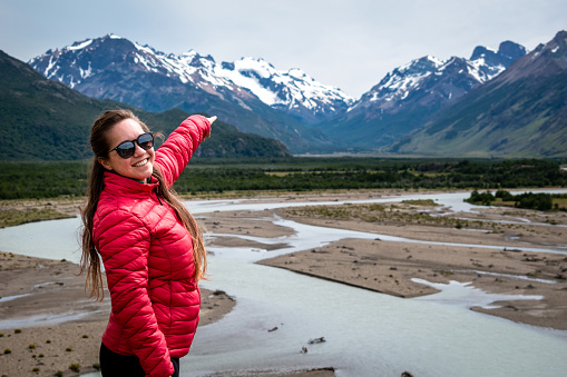 Tourist pointing finger at snowy mountain in the distance. Young woman in southern Argentina. Young tourist on vacation in El Chalten, Argentina. Tourist in Patagonia Argentina