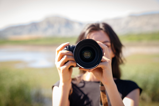 young woman using DSLR camera.Young woman photographer with camera lens