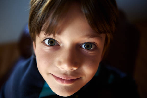 Young boy stare wide-eyed in shade room close up. Caucasian male child stare wide-eyed from darkening room close up. gawp stock pictures, royalty-free photos & images