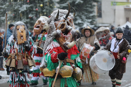 Breznik, Bulgaria - January 20, 2024: Unidentified people with traditional Kukeri costume are seen at the Festival of the Masquerade Games Surova in Breznik, Bulgaria.