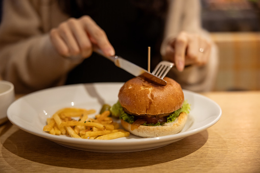 Woman eating hamburger for lunch in restaurant