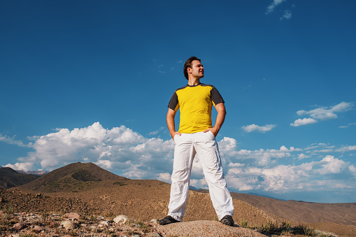 Handsome young man standing on mountains background and looking away