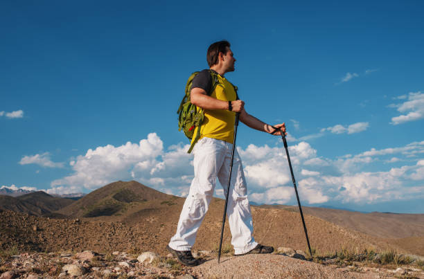 istock Man hiker with backpack and trekking poles standing in the mountains 1949910928