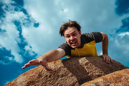 Male hiker on edge of cliff afraid to fall down, emotional portrait