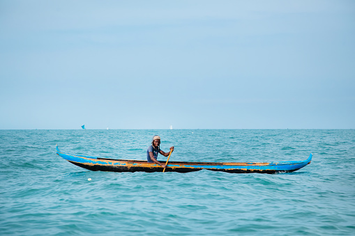 Morondava,Madagascar . 18 october 2023. Malagasy fisherman on homemade wooden old pirogue boat in ocean catches fish with net. selective focus, close-up view from ocean
