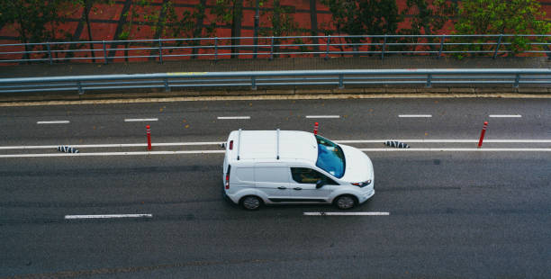 istock White car driving down the road in city 1949924655