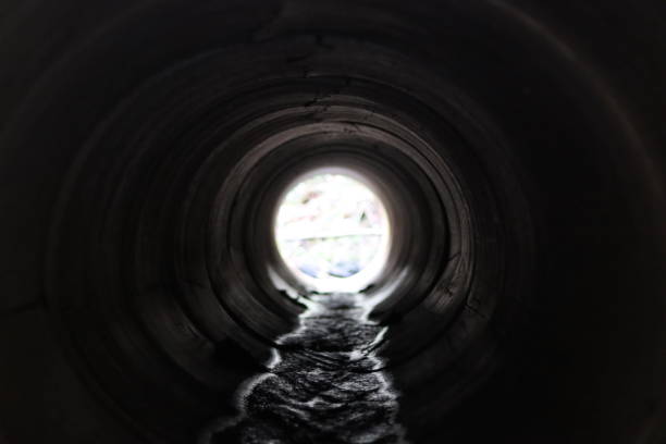 istock View through a round concrete tunnel carrying a stream beneath a road 1949935312
