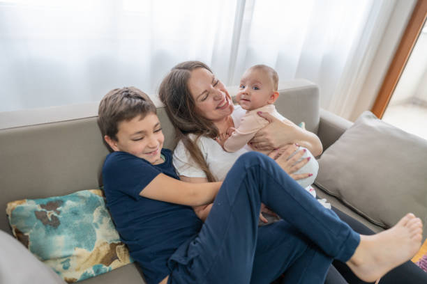 Mother playing with kids in living room smiling and having fun
