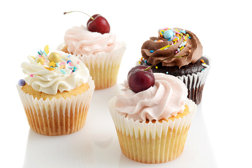 closeup of assorted buttercream cupcakes with white background
