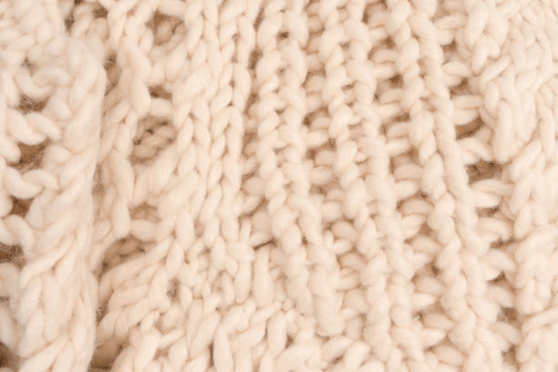 istock A fragment of beige knitted fabric, knitted from white sheep wool. 1949959347