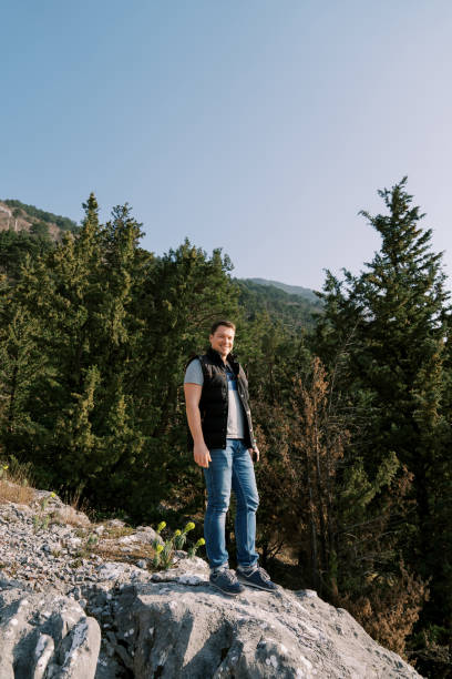 istock Smiling man stands on a stone hill in the mountains 1949976906