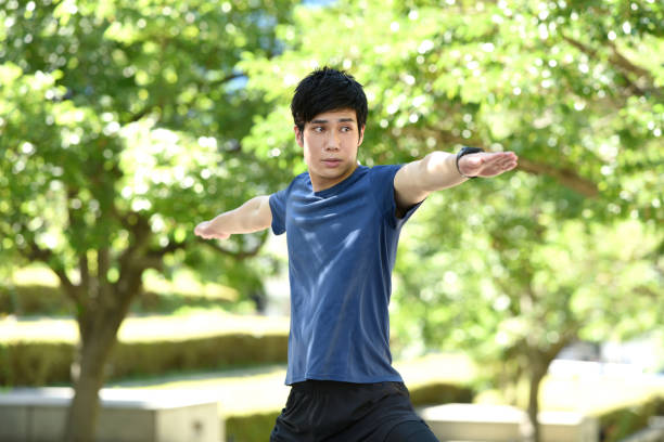 istock Young Asian man doing warrior pose during yoga lesson in nature 1949977957