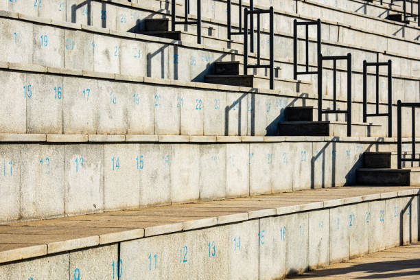 Urban concrete seating arrangement with wooden tops in sunlight casting shadows