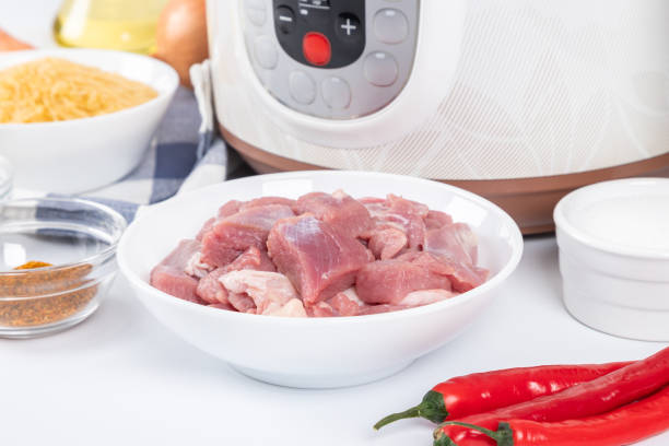 istock Prepared raw ingredients for cooking pilaf in modern multi cooker in kitchen on a table. Cooking pilau with meat in multicooker. 1950008402