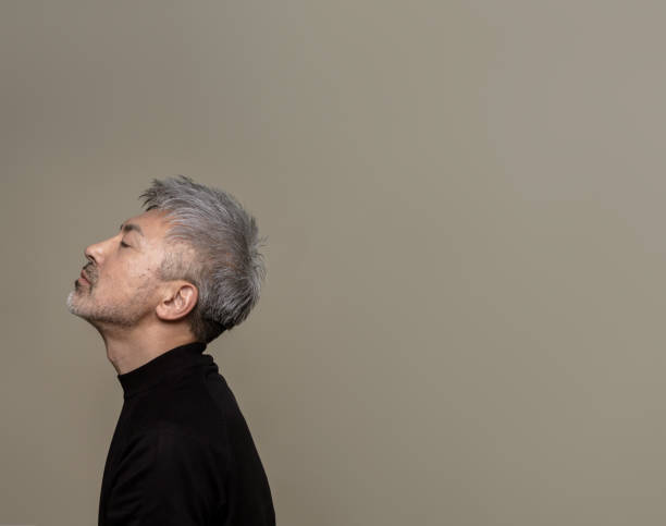 Portrait of a handsome middle-aged man with gray hair and a beard.He has his chin up and his eyes closed.