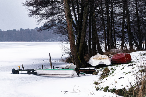 Frozen winter lake and old wooden boats on the shore. Winter landscape