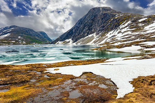 Lake Djupvatnet is covered with ice in July. Summer trip to Norway. The very cold clear water of the lake is covered with ice. Possession of Santa Claus.