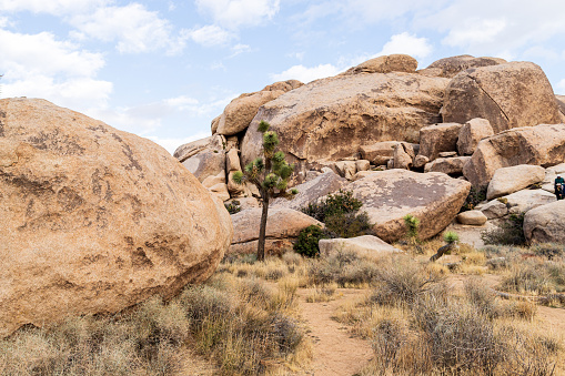 A red rock formation in the desert with a blue sky and clouds.