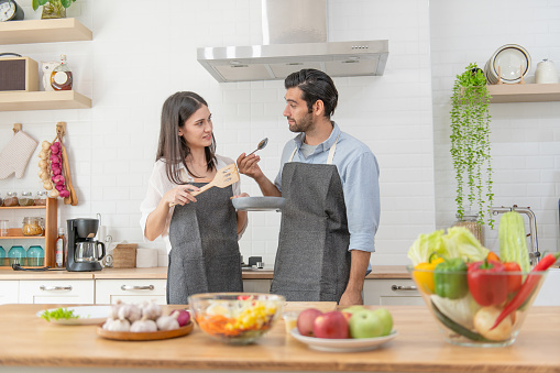 Happy young couple cooking together in the kitchen counter at home