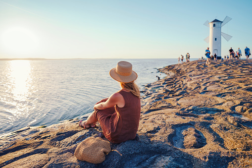 Woman enjoying sunset with white lighthouse in Swinoujscie city summer Poland