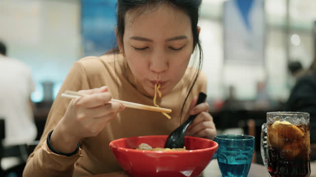Asian tourist woman eating Japanese Soba noodle in Japanese food restaurant.