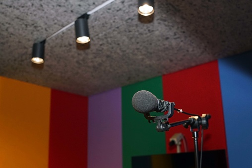 A microphone in the recording studio on the top a lights spot down, background with copy space.