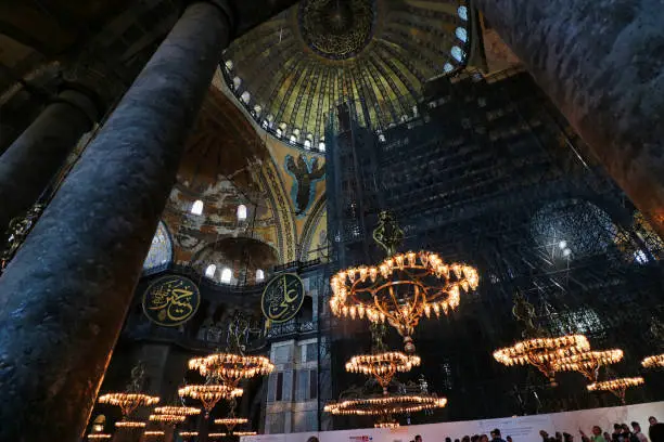 Grand Chandeliers with depictions of angels on the vaulted dome and arches inside the Hagia Sophia - landmark byzantine church built by Justinian in 537 AD in Istanbul, Turkey