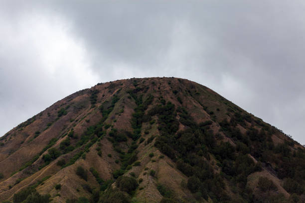 Landscape of green hills and village in a cloudy day. Mount Bromo is a volcano in Bromo Tengger Semeru National Park, East Java, Indonesia