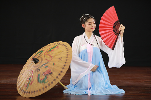 Traditional Japanese performance. Actress in white traditional japanese stage costume komono hits the drum.