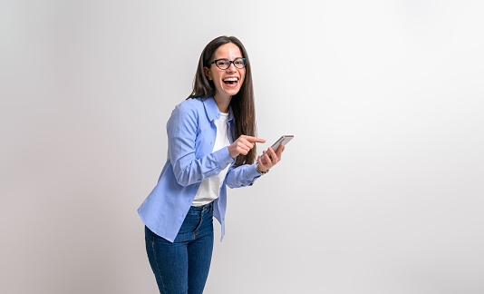 Portrait of female entrepreneur laughing and texting over smart phone on isolated white background