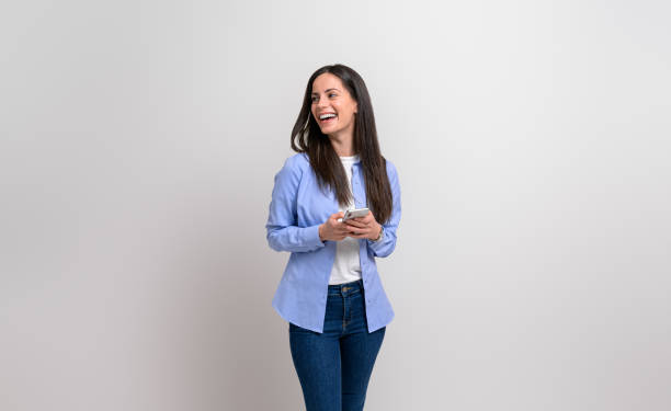 laughing businesswoman texting over smart phone and looking away on isolated white background - endast en kvinna bildbanksfoton och bilder