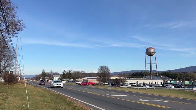 Passing Traffic on a Busy Road in Harrisonburg, Virginia in the Blue Ridge Mountains  on a Sunny Day with Light Clouds