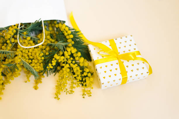 istock Beautiful flowers with package and present composition. Branches flowers mimosa on white background. Valentines Day, Easter, Birthday, Mother's day. Flat flat, top view, copy space. Spring Sale 1950259879