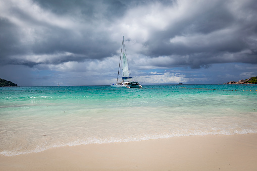 catamaran mooring under dramatic sky at praslin island, seychelles islands, indian ocean islands.