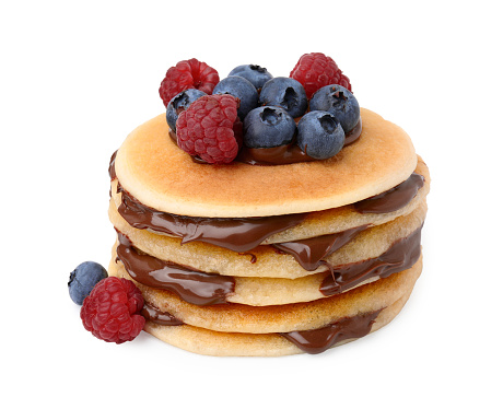 Stack of tasty pancakes with chocolate spread and berries isolated on white