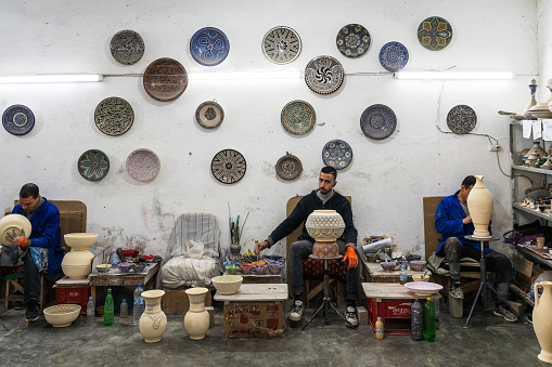 Fez, Morocco - January 01,  2024: Craftsman painting and decorating colorful ceramic products in pottery factory