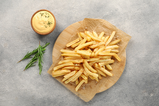 Delicious french fries served with sauce on grey table, flat lay