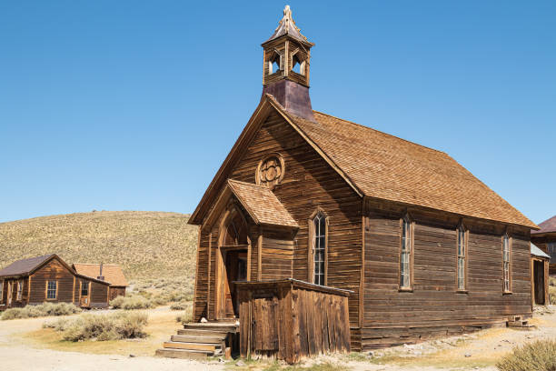 An abandoned ghost town church in Bodie State Park in the arid desert landscape of California, USA with a cloudless blue sky.