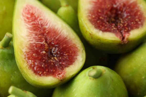 istock Cut and whole fresh green figs as background, closeup view 1950288779