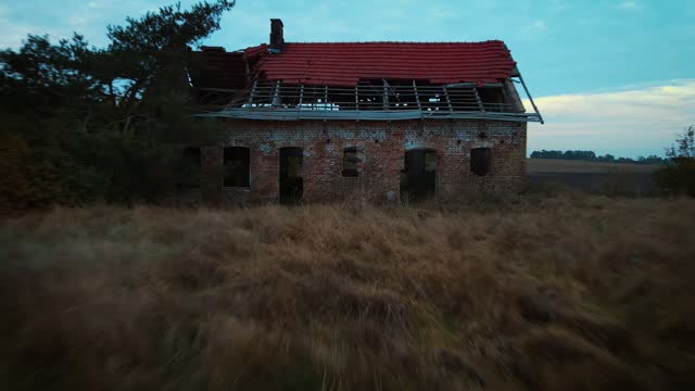 Ruins of home. Abandoned and decaying old house. Peeling paint broken windows and overgrown vegetation creating haunting and melancholic atmosphere