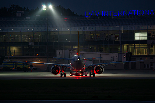 An aircraft being pushed back from Lviv Airport Terminal at night before its departure