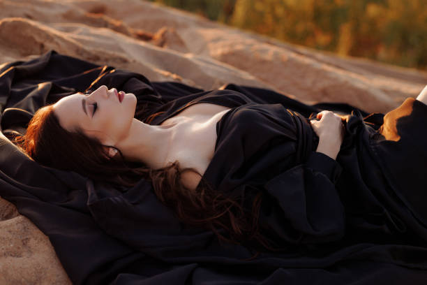 Goth lady of 30 outdoors by an old wooden gate.