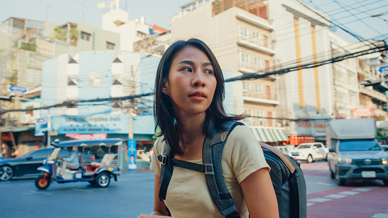 Young Asian woman backpacker walking along on the street at Bangkok, Thailand. Holiday vacation trip concept.