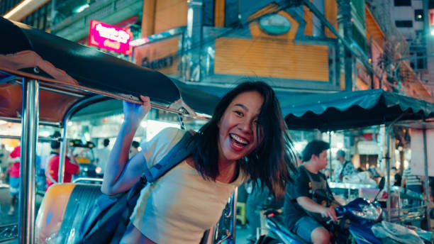 Young Asian woman tourist traveling by a Tuk Tuk vehicle on the street at Bangkok, Thailand. Holiday vacation trip. Young Asian woman tourist traveling by a Tuk Tuk vehicle on the street at Bangkok, Thailand. Holiday vacation trip concept. night market stock pictures, royalty-free photos & images